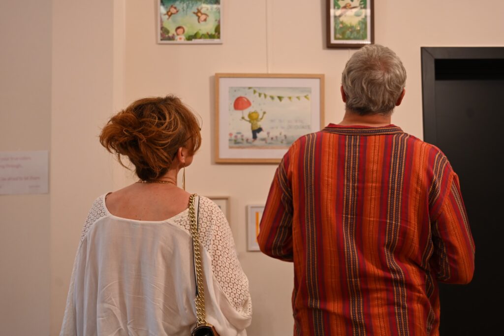 Visiteurs découvrant les illustrations de l'exposition Escapades au jardin à Mons